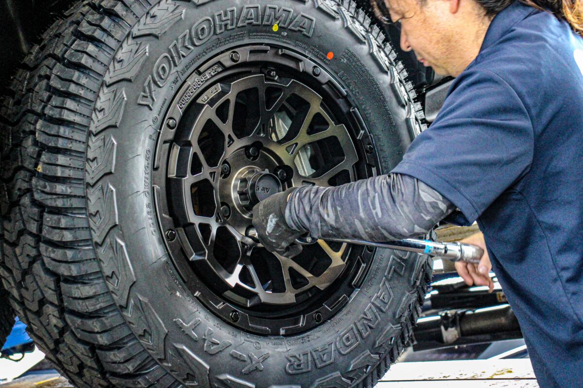 新型ハイラックスをリフトアップし、Air/G Rocks装着時の干渉やクリアランスをプロの目線で慎重に確認している作業中の一幕